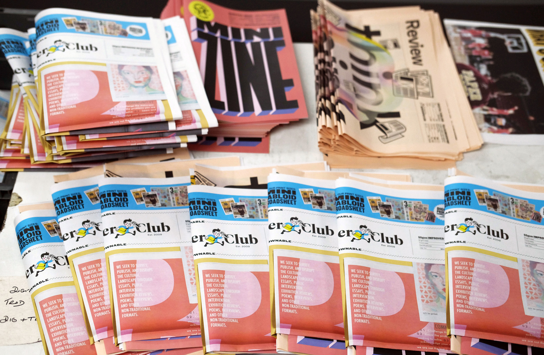 A table containing a colorful array of newspaper samples of different sizes and shapes.